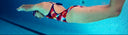 Person swimming underwater in a pool with lane dividers.