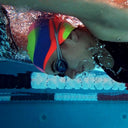Person swimming underwater with a colorful swim cap and goggles.