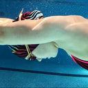 Person swimming underwater in a pool with lane dividers.