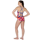 Woman wearing a colorful tie-dye swimsuit with blue straps on a white background