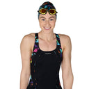 Person wearing a black swimsuit with colorful patterns, swim cap, and goggles on a white background